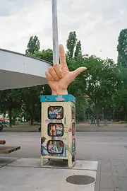 Cabine téléphonique avec au-dessus une sculpture d’une main sur le Meidlinger Markt