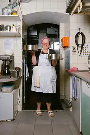 Cuisinière de la Vollpension, debout dans la cuisine et tenant un plateau