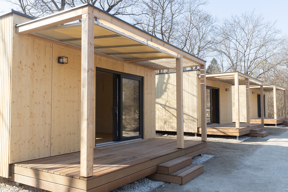 Trzy małe drewniane bungalowy z zadaszonym tarasem na kempingu Wien Wienerwald