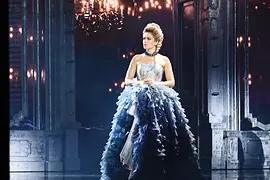 Maria Theresia allein auf der von Kerzenlustern erleuchteten Bühne in langer blauer Robe.