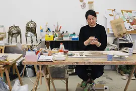Onka Allmayer-Beck modeling clay at the table in her studio