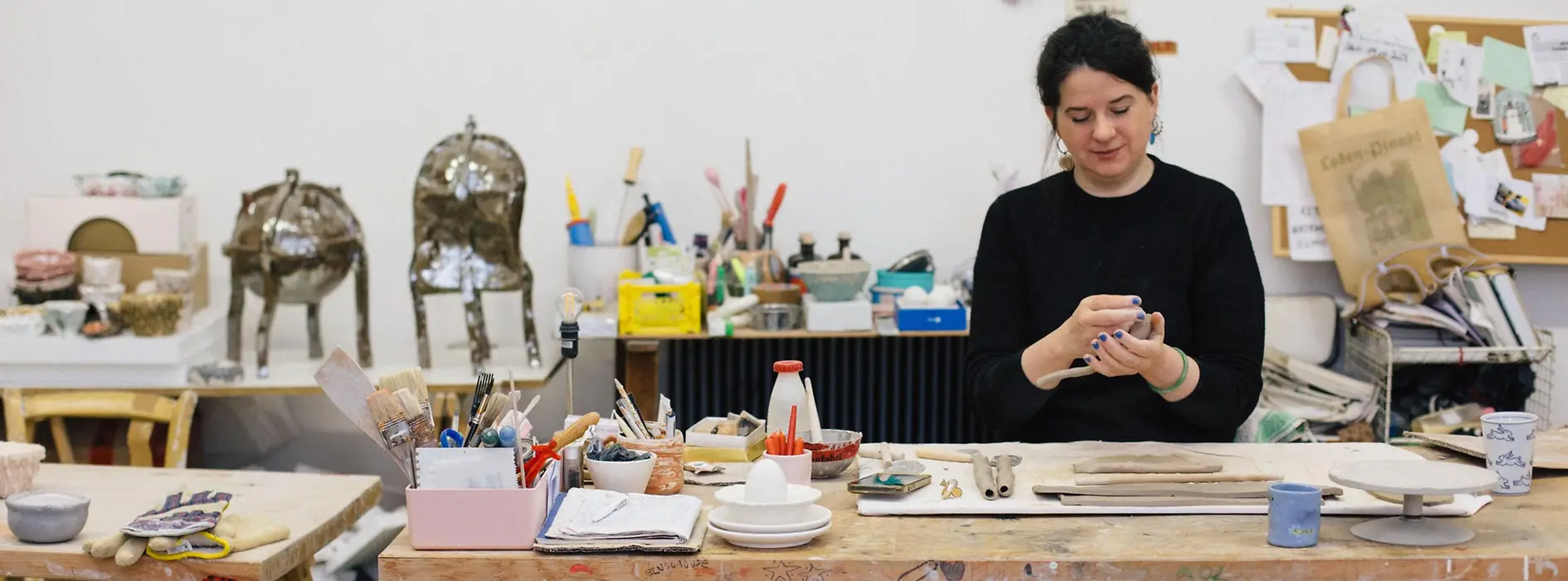 Onka Allmayer-Beck modeling clay at the table in her studio