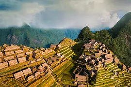 Aerial view of the Machu Picchu ruins in the Peruvian Andes, surrounded by misty mountains. 