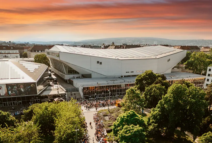 Aerial view of the Wiener Stadthalle at dusk, with people waiting to enter.