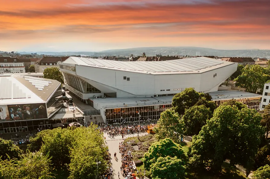 Vista aérea del Wiener Stadthalle al atardecer, personas esperan para entrar.
