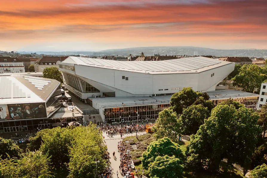 Luftaufnahme der Wiener Stadthalle in Abendstimmung, Menschen warten auf den Einlass