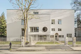 Straßenansicht der modernistischen Villa mit rundem Fenster und zurückgesetztem Eingang.