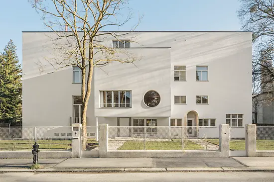 Straßenansicht der modernistischen Villa mit rundem Fenster und zurückgesetztem Eingang.