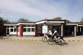 Zwei Radfahrer vor dem Eingangsbereich des Campingplatzes MICAMPA Wien Donau