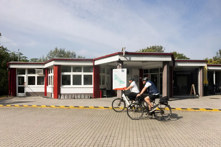 Zwei Radfahrer vor dem Eingangsbereich des Campingplatzes MICAMPA Wien Donau