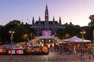 Blick auf die belebte Gastromeile beim Film Festival, dahinter das Wiener Rathaus.