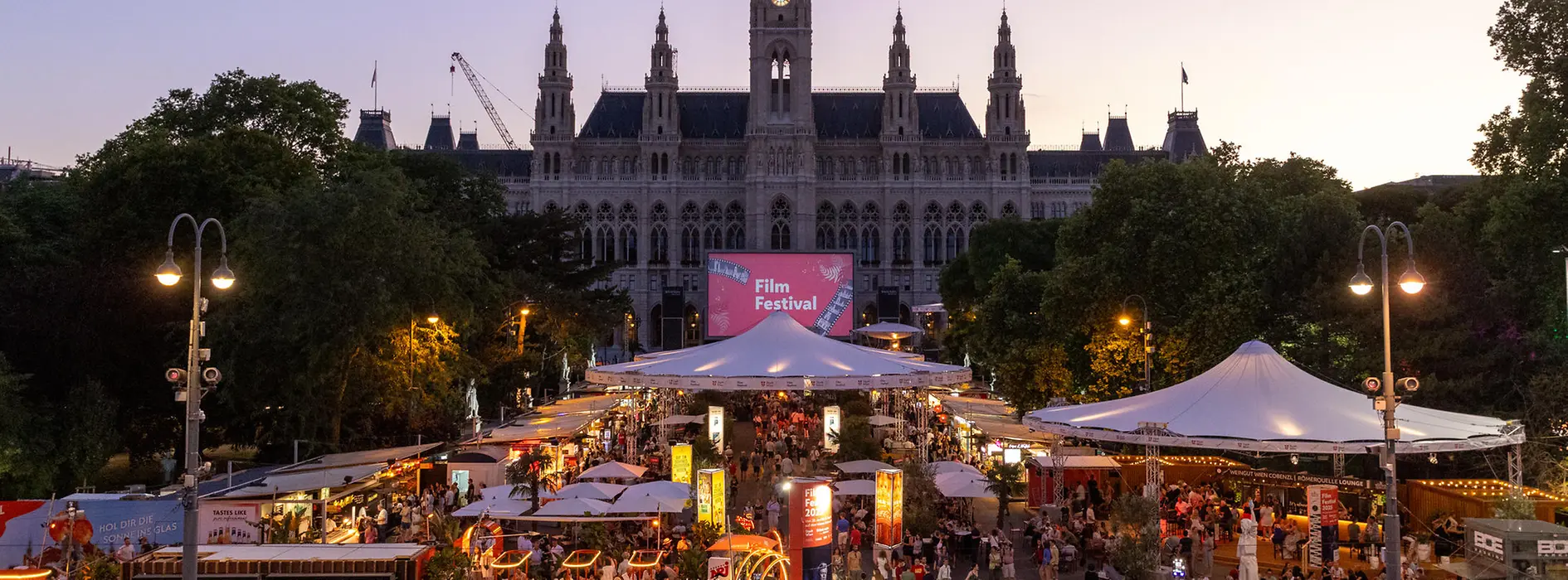 Blick auf die belebte Gastromeile beim Film Festival, dahinter das Wiener Rathaus.