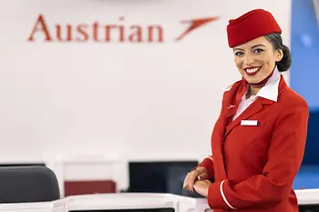 Azafata de Austrian Airlines con uniforme de cabina rojo.