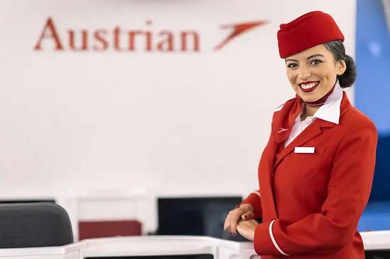 Hôtesse de l’air d’Austrian Airlines en uniforme de bord rouge.