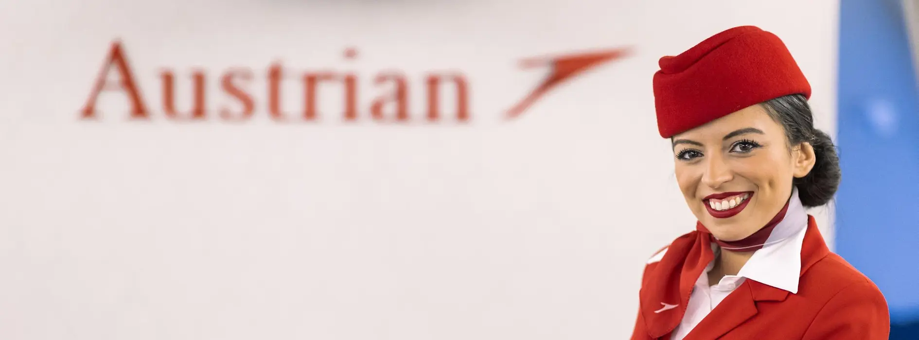Azafata de Austrian Airlines con uniforme de cabina rojo.