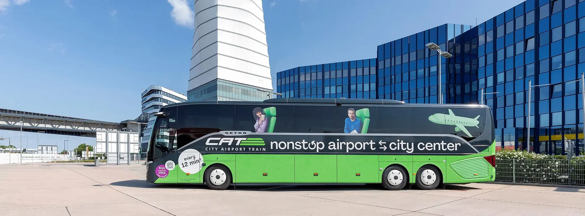 City Airport Train express bus in front of the control tower at Vienna Airport, with the terminal building in the background.