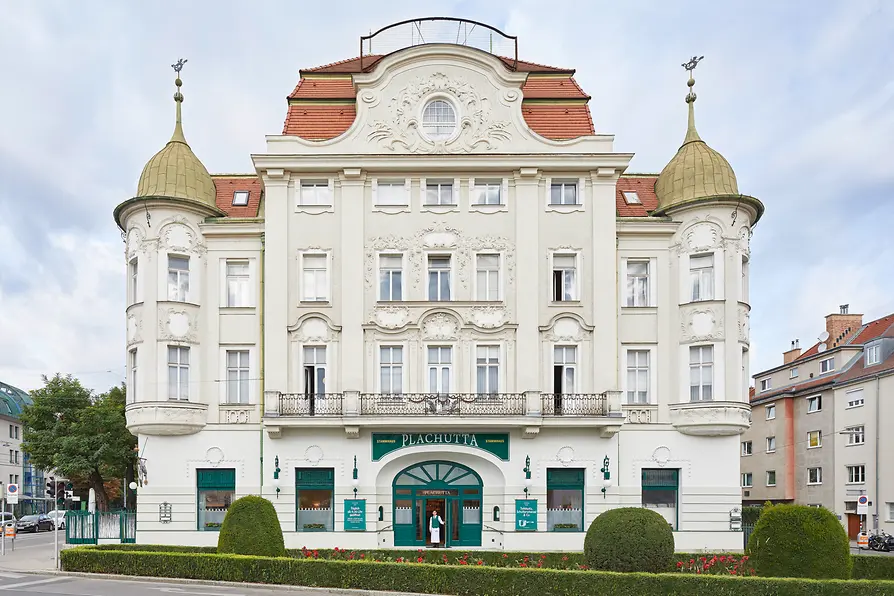 Fassade des Plachutta-Stammhauses in Hietzing mit reich verzierter Architektur und begrüntem Vorgarten.