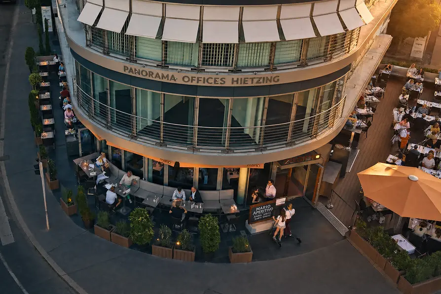Luftaufnahme des Restaurants Mario mit großzügigen Terrassen und zahlreichen Gästen bei Sonnenuntergang.