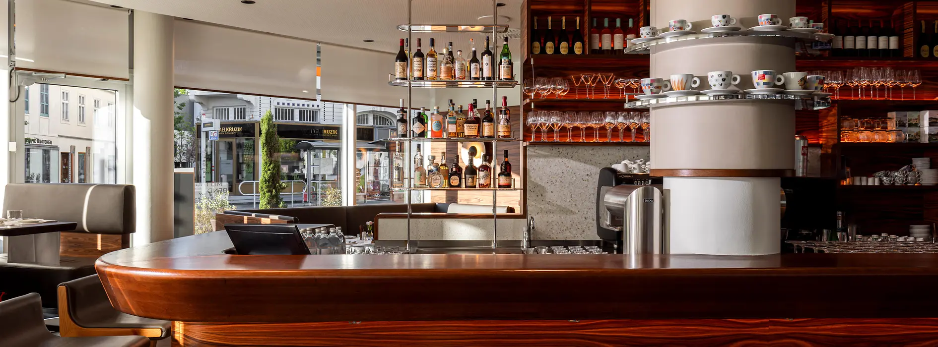 Innenansicht der Mario-Bar mit Holztheke, Kaffeemaschine, Spirituosen und Gläsern.