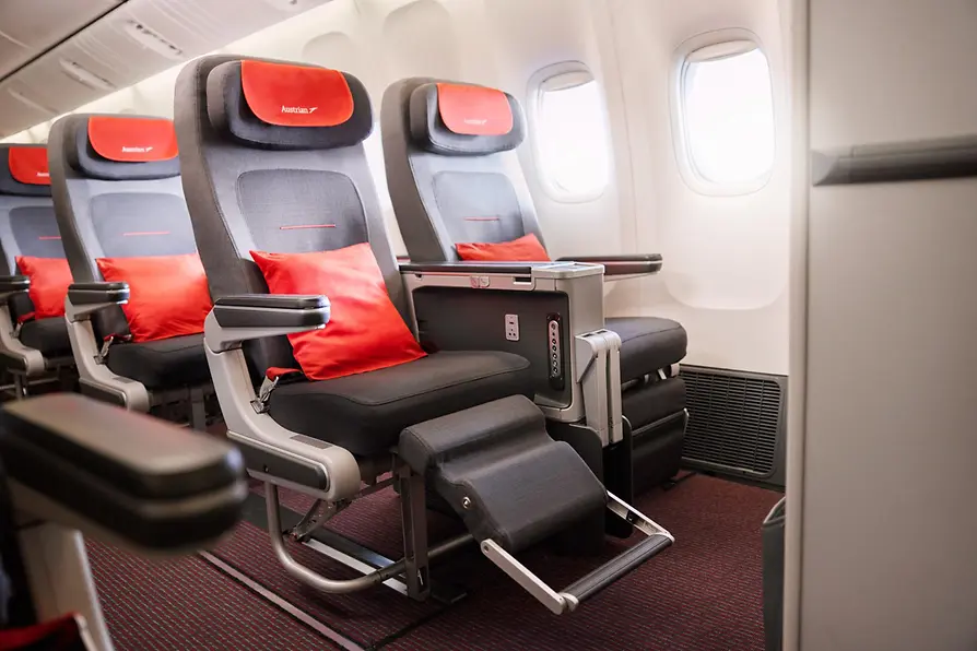 Flugzeugsitze mit roten Polstern von Austrian Airlines in der Reiseklasse Premium Economy.