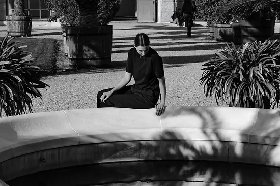 Una mujer sentada junto al estanque de la fuente