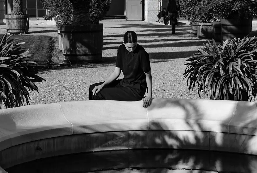 Una mujer sentada junto al estanque de la fuente