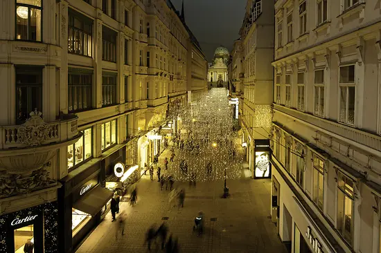 Gente a passeggio di notte nella piazza Kohlmarkt suggestivamente illuminata