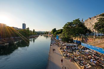 Люди в шезлонгах в лучах солнца на Дунайском канале