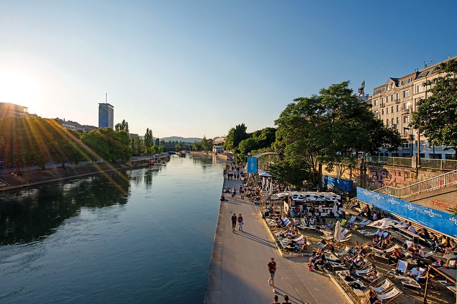 People lying in the sun on loungers by the Danube Canal