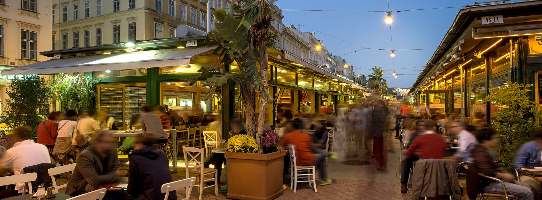 Bustling scene in the pubs and cafes at Naschmarkt, exterior shot with people 