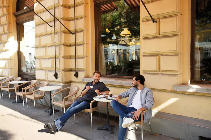 Zwei Männer trinken Café vor einem Wiener Kaffeehaus