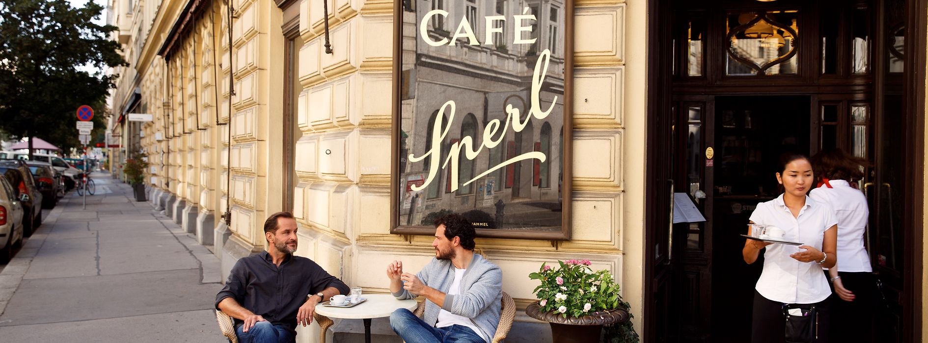 Two men sitting in front of a coffee house 