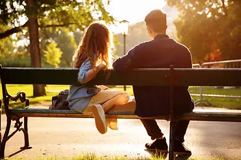 Mladý pár sedící na lavičce v parku v zámecké zahradě