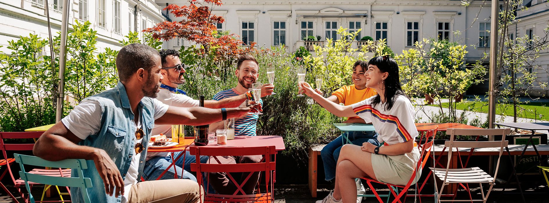 Gruppe junger Leute trinkt gemeinsam in einem Schanigarten