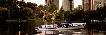 A man and a woman jump from a boat into the water
