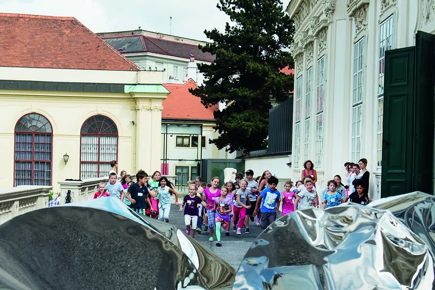 Group of children outside Belvedere, running towards an metallic object