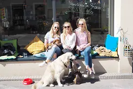 Three young women sitting on a window bench in a café
