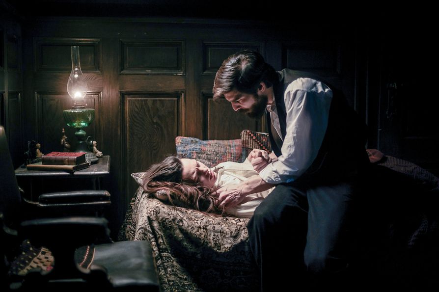 Freud (Robert Finster) ukrývá viditelně vyčerpanou Fleur (Ella Rumpf), ležící na nízké pohovce, a drží ji za ruku.