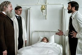 Freud (Robert Finster) is talking to other doctors at the hospital bed of a young patient. 