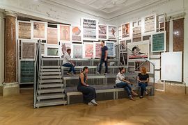 Trybuna z ludźmi przed plakatami w Haus der Geschichte Österreich