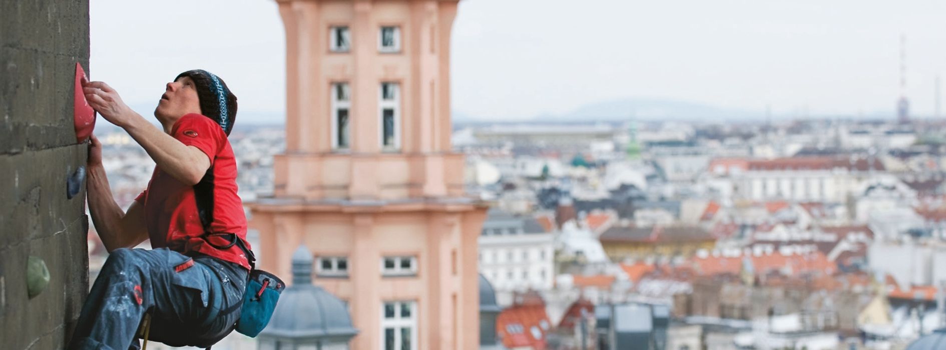 Mann klettert am Flakturm vor Wien-Panorama