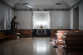 Rakve v síni, socha a osvětlený oltář