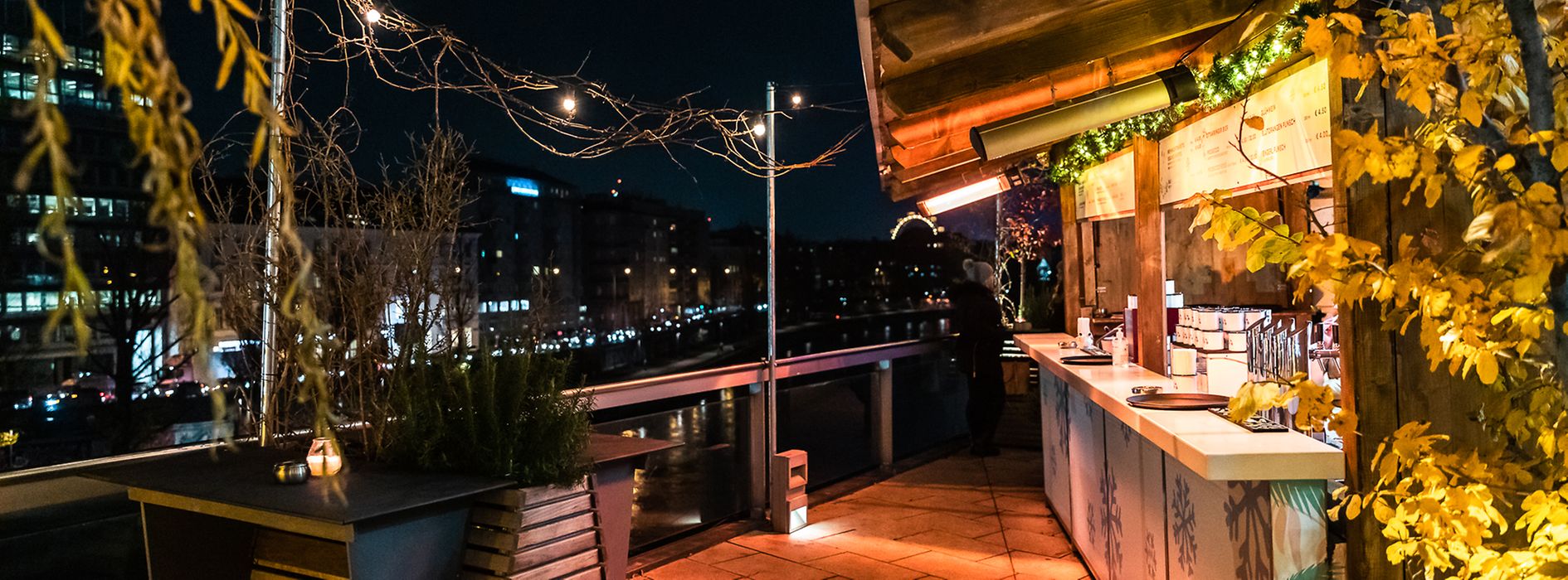 Menschen trinken Punsch auf einer Terrasse mit Blick auf Donaukanal