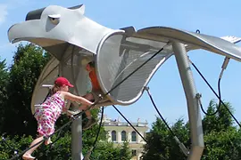 Two children climbing on playground equipment that looks like an eagle