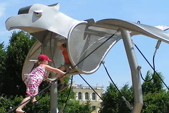 Two children climbing on playground equipment that looks like an eagle