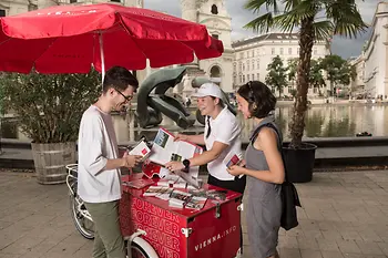 Bike, people standing holding looking at brochures 