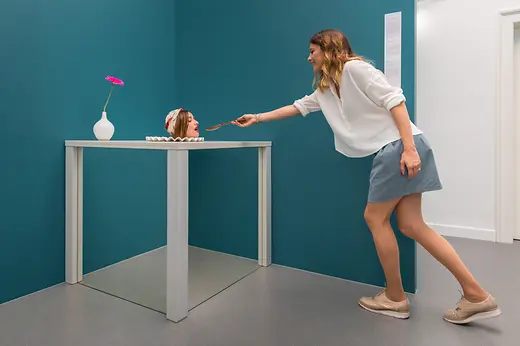 Museo delle illusioni, donna nutre la testa su un tavolo