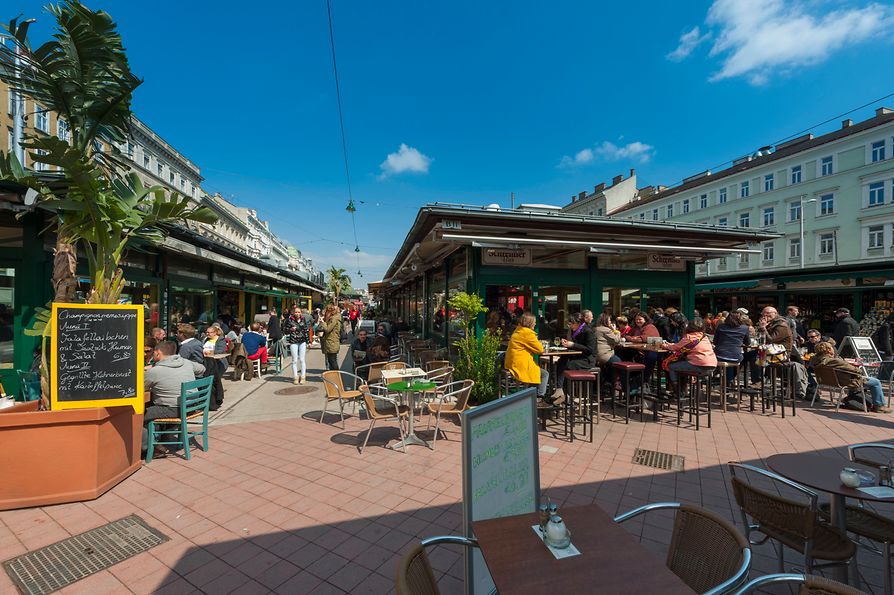 Bustling scene in the pubs and cafes at Naschmarkt, exterior shot with people 