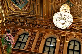 Goldener Saal im Musikverein, Blick auf die Decke mit erleuchtetem Luster, Blumenschmuck an Balustrade