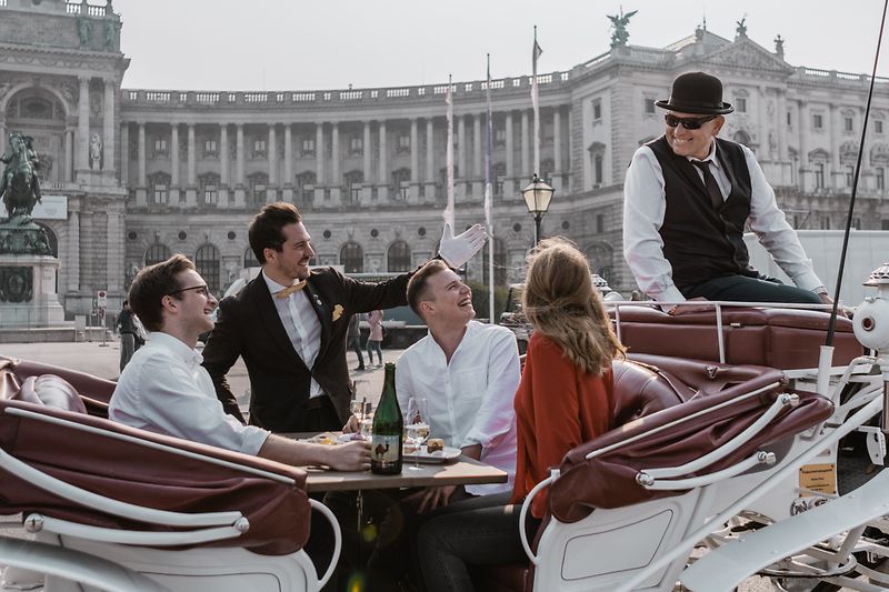 Menschen beim Essen in einem Fiaker vor der Hofburg